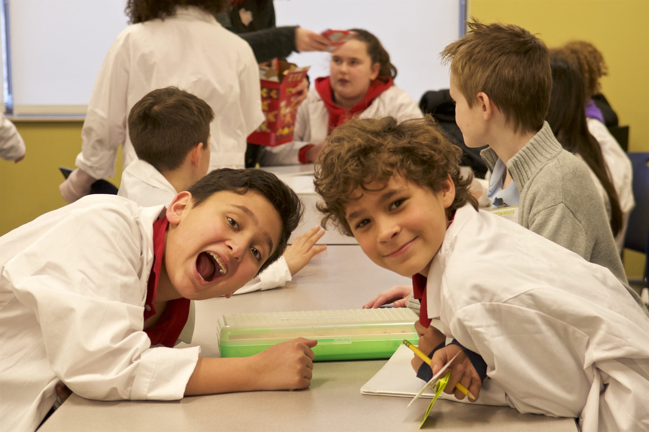 Students in lab coats smile at the camera